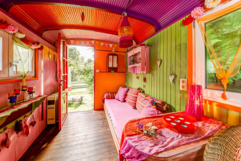 Colorful mobile home interior with vibrant decor and cushions at Les Roulottes de Vio in Belgium.