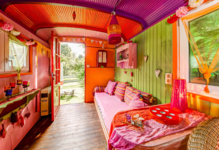 Colorful mobile home interior with vibrant decor and cushions at Les Roulottes de Vio in Belgium.