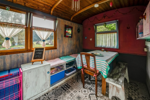 Cozy interior of a mobile home at 'Les Roulottes de Vio' in Belgium, featuring a dining table and colorful decor.