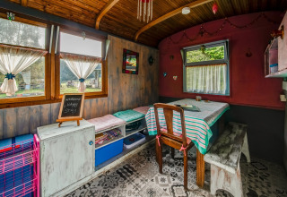 Cozy interior of a mobile home at 'Les Roulottes de Vio' in Belgium, featuring a dining table and colorful decor.