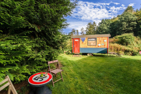 A cozy mobile home at Les Roulottes de Vio in Belgium, with outdoor seating and lush green surroundings.