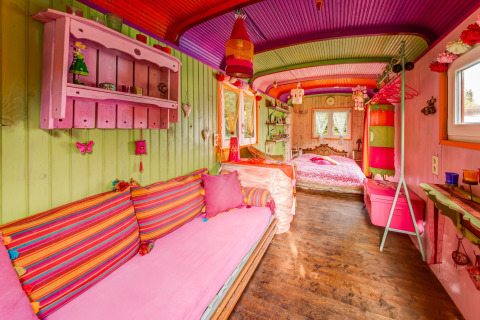 Colorful mobile home interior at 'Les Roulottes de Vio' in Belgium, featuring bright decor and wooden walls.