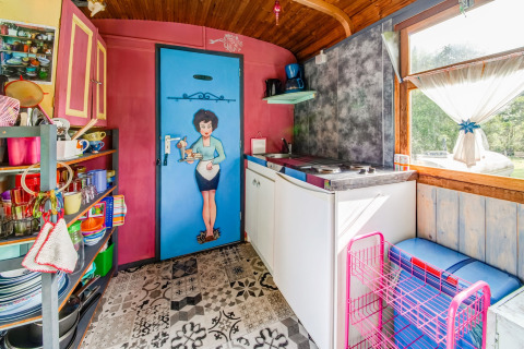 Colorful kitchen inside the mobile home 'Les Roulottes de Vio' with retro decor and countryside views in Belgium.