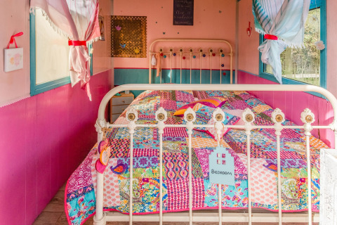 Colorful bedroom inside the mobile home 'Les Roulottes de Vio' in Belgium, featuring a patchwork quilt.