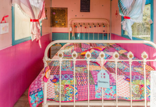 Colorful bedroom inside the mobile home 'Les Roulottes de Vio' in Belgium, featuring a patchwork quilt.
