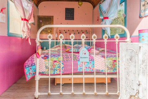 Colorful bedroom with a patchwork quilt in the mobile home Les Roulottes de Vio located in Belgium.