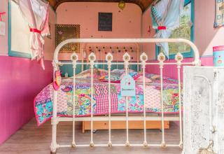 Colorful bedroom with a patchwork quilt in the mobile home Les Roulottes de Vio located in Belgium.