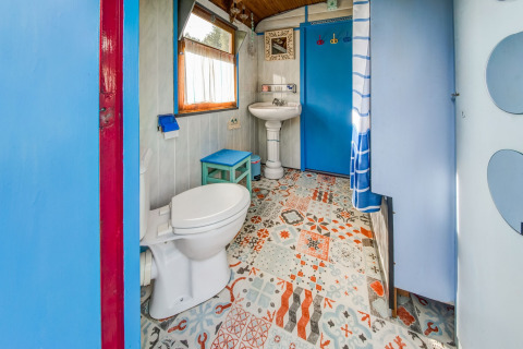 Colorful bathroom in Les Roulottes de Vio mobile home in Belgium with patterned floor and blue accents.