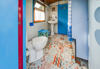 Colorful bathroom in Les Roulottes de Vio mobile home in Belgium with patterned floor and blue accents.