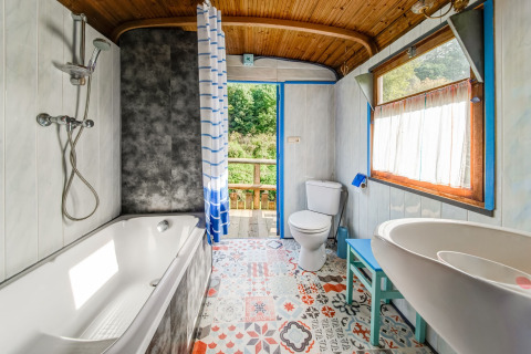 Bright bathroom in mobile home with bathtub, toilet, and colorful tiles at Les Roulottes de Vio, Belgium.
