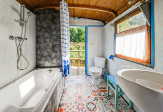 Bright bathroom in mobile home with bathtub, toilet, and colorful tiles at Les Roulottes de Vio, Belgium.