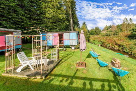 Les Roulottes de Vio mobile home in Belgium, with colorful wagons, deck chairs, and meadow seating area.