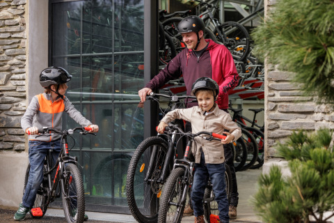 Gezin met helmen maakt zich klaar voor een fietstocht bij een glamping-accommodatie met fietsen zichtbaar.
