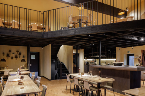 Interieurfoto van een gezellig restaurant met houten tafels en entresol bij een glamping-accommodatie.