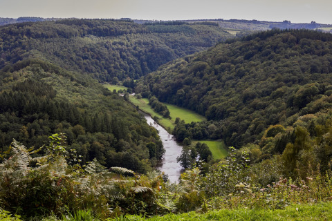 Panoramisch uitzicht op een rivierdal tussen groene heuvels vlakbij een glamping accommodatie in de natuur.