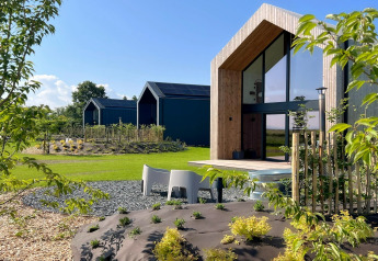 Cabaña moderna llamada 'Natural Escape' en Bélgica, con grandes ventanales, detalles en madera y jardín