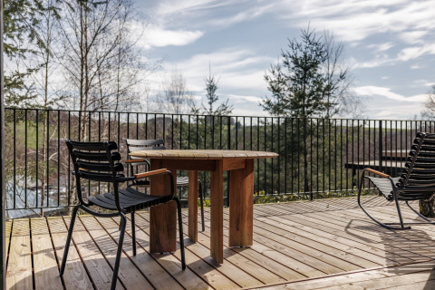 Buitenterras bij Hillview Resort Grandvoir 1 in België met houten tafel, stoelen en uitzicht op het bos.