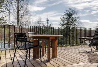 Buitenterras bij Hillview Resort Grandvoir 1 in België met houten tafel, stoelen en uitzicht op het bos.