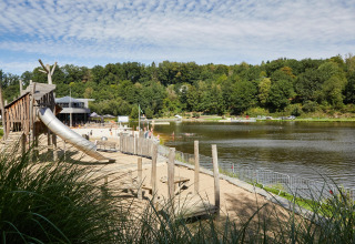 Strand aan het meer met speeltuin en glijbaan bij Hillview Resort Grandvoir 1 in België, omringd door bos.
