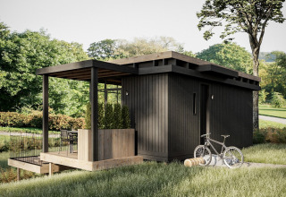 Moderne zwarte houten cabin bij Hillview Resort Grandvoir 1 in België met terras, fiets en groene natuur.