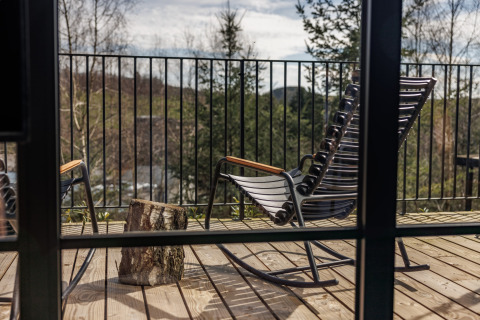 Uitzicht vanuit een blokhut bij Hillview Resort Grandvoir 1 in België met schommelstoelen op het terras.