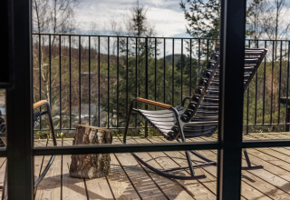 Uitzicht vanuit een blokhut bij Hillview Resort Grandvoir 1 in België met schommelstoelen op het terras.
