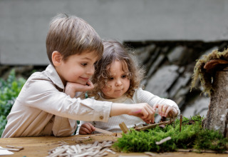 Twee kinderen spelen creatief met natuurlijke materialen bij Hillview Resort Grandvoir 1, België.