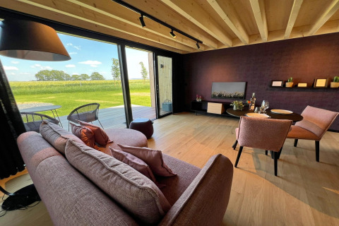 Et hyggeligt opholdsområde i kabinen 'Natural Escape' i Belgien med udsigt over en smuk eng.