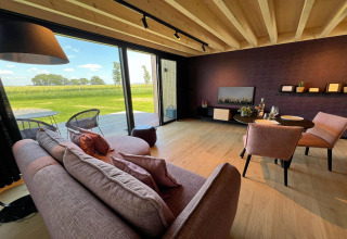 Et hyggeligt opholdsområde i kabinen 'Natural Escape' i Belgien med udsigt over en smuk eng.