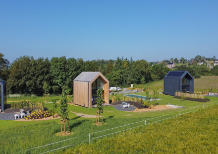Luchtfoto van twee moderne hutten bij Natural Escape, omringd door groene velden, bomen en paden.