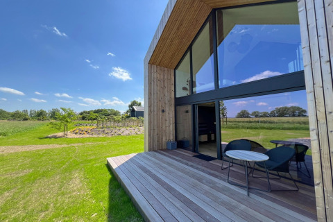 Solrigt udsyn fra terrassen på hytten 'Natural Escape' i Belgien, omgivet af grønt landskab.