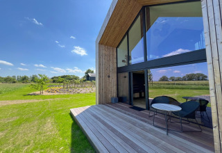 Solrigt udsyn fra terrassen på hytten 'Natural Escape' i Belgien, omgivet af grønt landskab.