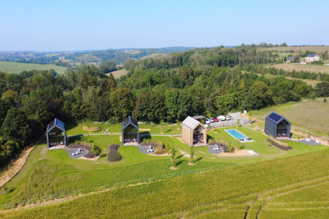 Luftfoto af Natural Escape hytter med swimmingpool og frodige grønne marker i Belgien.