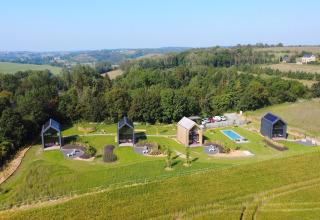 Luftfoto af Natural Escape hytter med swimmingpool og frodige grønne marker i Belgien.