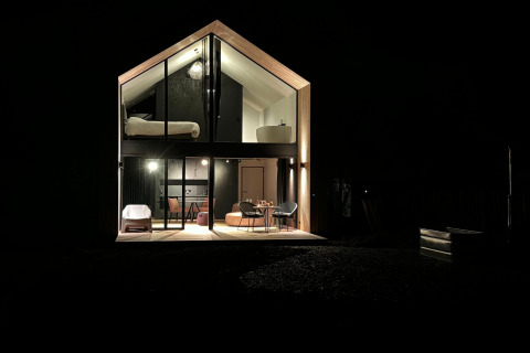 Natfotografering af kabinen 'Natural Escape' i Belgien, moderne glasfacade og hyggelig belysning.