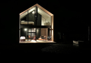 Natfotografering af kabinen 'Natural Escape' i Belgien, moderne glasfacade og hyggelig belysning.