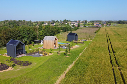 Naturskøn udsigt over moderne hytter ved Natural Escape i Belgien med grønne marker og landsby.
