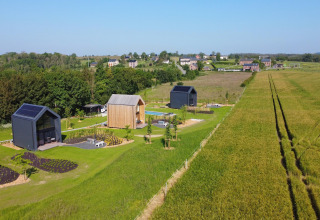 Naturskøn udsigt over moderne hytter ved Natural Escape i Belgien med grønne marker og landsby.