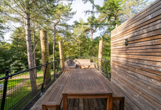Outdoor deck at The TreeLoft with wooden furniture, surrounded by tall trees and lush forest scenery.