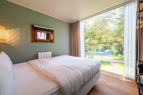 Camera da letto al TreeLoft di YourNature con ampia finestra, vista sul bosco e arredo moderno e accogliente.