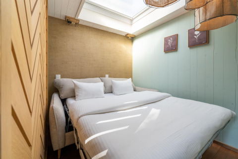 Bright bedroom in the TreeLoft by YourNature treehouse, featuring a skylight, cozy bed, and minimalist décor.