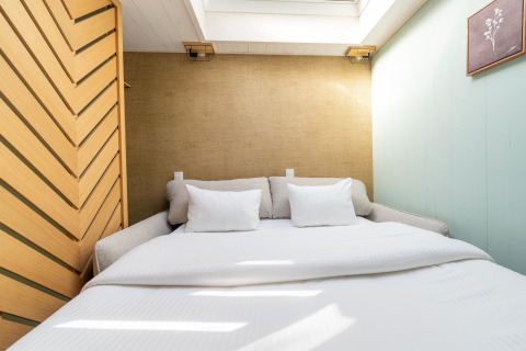 Camera da letto con letto matrimoniale, cuscini bianchi e lucernario presso The TreeLoft by YourNature, una casa sull'albero.