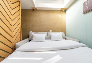 Camera da letto con letto matrimoniale, cuscini bianchi e lucernario presso The TreeLoft by YourNature, una casa sull'albero.