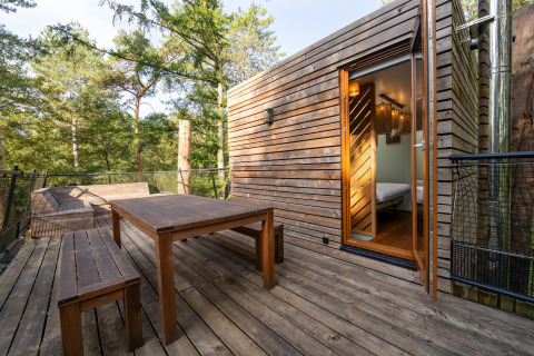 Treehouse deck with wooden table and benches overlooking forest, photo taken at The TreeLoft by YourNature.