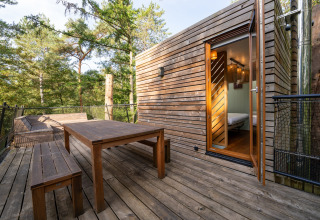 Treehouse deck with wooden table and benches overlooking forest, photo taken at The TreeLoft by YourNature.