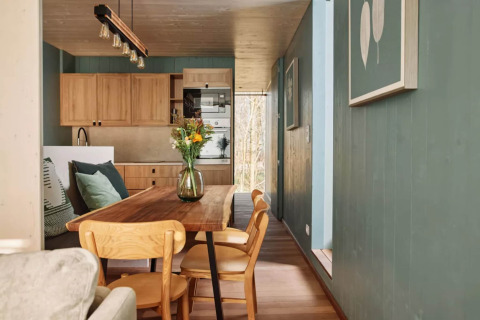 Dining area and kitchen at The TreeLoft by YourNature, featuring wood interiors, green walls and flowers.