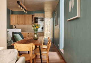 Dining area and kitchen at The TreeLoft by YourNature, featuring wood interiors, green walls and flowers.