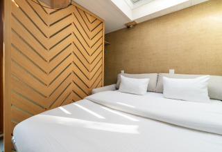 Modern bedroom in The TreeLoft by YourNature featuring a cozy bed, white bedding, and wooden divider.