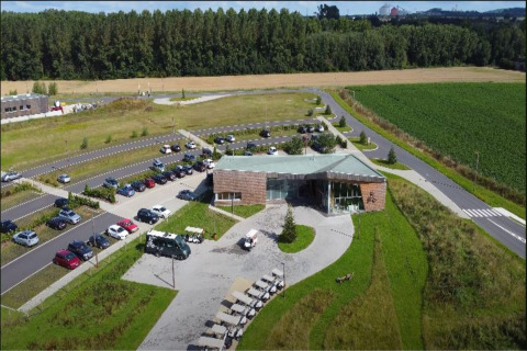 Luftfoto af The TreeLoft by YourNature i Belgien, omgivet af grønt landskab og parkering.