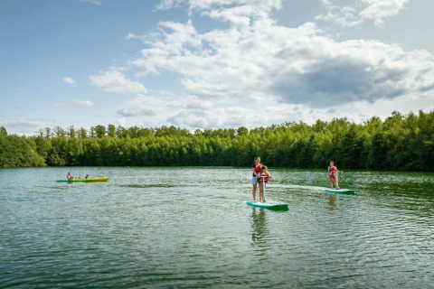 Folk nyder stand up paddleboarding og kajaksejlads på en sø ved The TreeLoft by YourNature i Belgien.